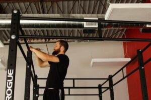 A man named Miles Brown working on a pull-up bar in a gym.