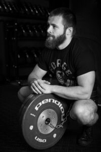 Miles Brown, a man with a beard, crouching down with a barbell.