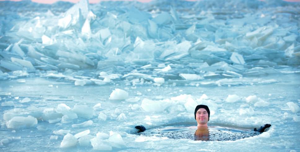 A man is floating in the middle of an ice floe, experiencing the chilling effects of ice baths.