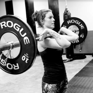 A woman at a Wichita Personal Training Studio, confidently holding a barbell as she works out in the gym.