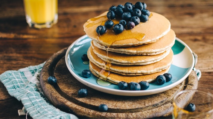 A stack of pancakes with blueberries on a plate, making it a delicious breakfast option.