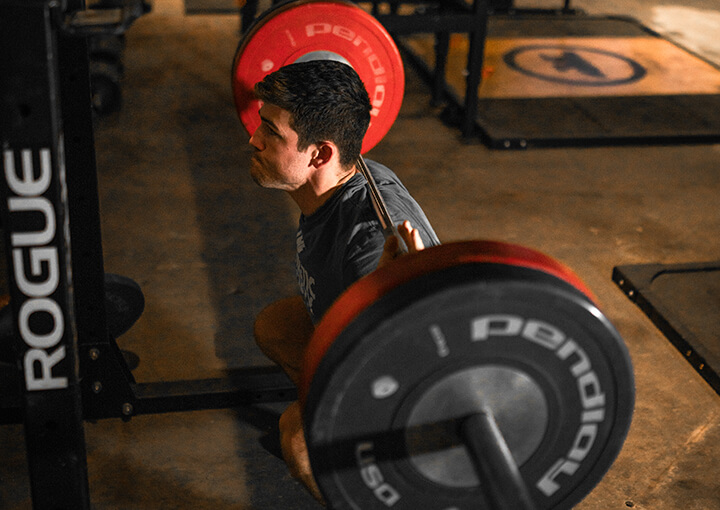 A man squatting with a red-black colored barbell