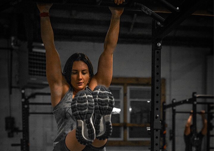 A woman doing hanging leg raise in a gym.